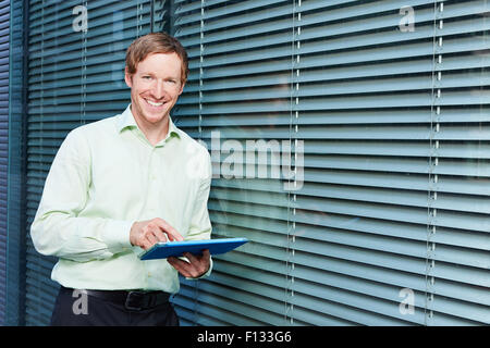 Smiling businessman with tablet computer à côté de son bureau Banque D'Images