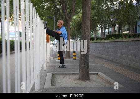 Beijing, Chine. Août 26, 2015. Un vieil homme s'étend sur une clôture à l'extérieur le stade national, également connu sous le nom de nid d'oiseau, pendant les Championnats du monde IAAF 2015 à Beijing, Chine, 26 août 2015. Photo : Christian Charisius/dpa/Alamy Live News Banque D'Images