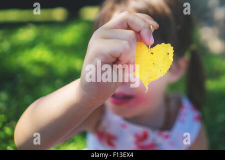 Girl holding a leaf en face de son visage Banque D'Images