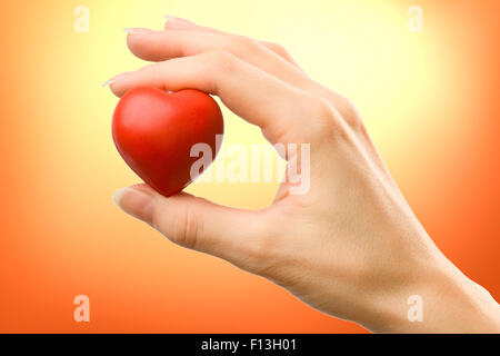 Coeur rouge avec main de femme tenant soigneusement Banque D'Images