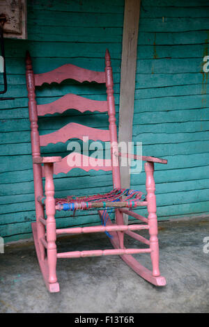 Une vieille chaise à bascule en bois rose assis sur un porche Banque D'Images
