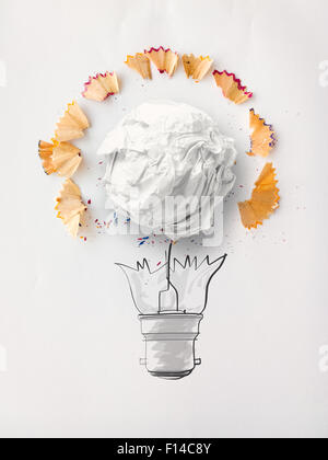 L'ampoule à la main et au crayon de papier froissé sciure sur papier fond comme concept créatif Banque D'Images