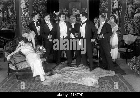 Années 1920 FEMME ÉVANOUISSEMENT COMME GROUPE D'HOMMES HABILLÉS FORMELLEMENT AUTOUR DE STAND ENCORE Film muet Banque D'Images