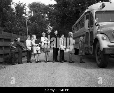 1960 LIGNE D'ENFANTS EN ATTENTE D'OBTENIR SUR SCHOOL BUS Banque D'Images