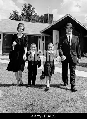 1960 SMILING WOMAN FAMILLE DE QUATRE Mère Père Fils Fille MARCHE LOIN DE CHURCH LOOKING AT CAMERA Banque D'Images