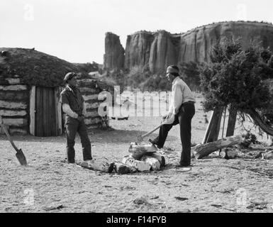 Années 30, DEUX HOMMES NAVAJO NATIVE AMERICAN DIVISION FIRE WOOD AVEC AX ACCUEIL TRADITIONNEL HOGAN EST EN ARRIÈRE-PLAN Banque D'Images