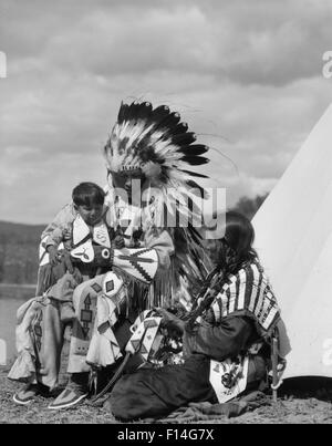 Années 1920 NATIVE AMERICAN FAMILY HOMME FEMME GARÇON COSTUME COIFFE DE PLUMES PLEIN TRIBU SIOUX STONEY ALBERTA CANADA Banque D'Images