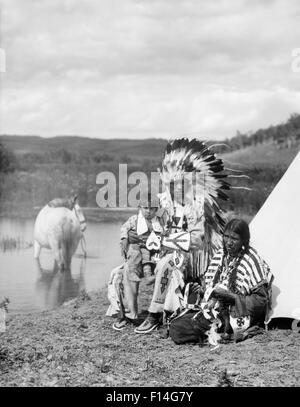 Années 1920 NATIVE AMERICAN FAMILY HOMME FEMME ENFANT CHEVAL PAR TEPEE À PLUMES PLEIN DE COSTUMES PERLÉS SIOUX STONEY TRIBE ALBERTA CANADA Banque D'Images