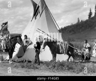 Années 1920, les Indiens sioux STONEY GROUP HOMMES ET FEMMES À CHEVAL TIRANT UN TRAVOIS PAR TEPEE ALBERTA CANADA Banque D'Images