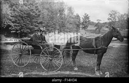 1890 1890 DÉBUT DU 20ème siècle COUPLE HOMME FEMME ÉQUITATION DE CHEVAL CHARIOT BUGGY LOOKING AT CAMERA Banque D'Images