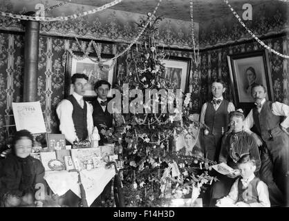 1890 1890 TOUR DU SIÈCLE PORTRAIT DE GROUPE DE TROIS GÉNÉRATIONS DE LA FAMILLE POSE PAR ARBRE DE NOËL CADEAUX SUR LA TABLE Banque D'Images