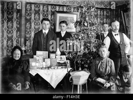 1890 1890 TOUR DU SIÈCLE PORTRAIT DE GROUPE DE TROIS GÉNÉRATIONS DE LA FAMILLE POSE PAR ARBRE DE NOËL CADEAUX SUR LA TABLE Banque D'Images