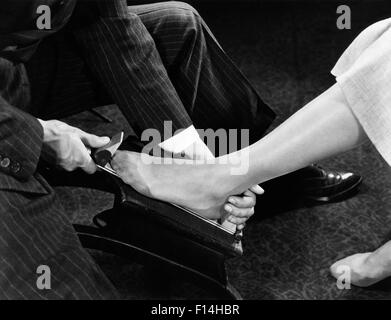 1940 Close-up of SHOE SALESMAN MAINS PIEDS FEMME DE MESURE POUR LA TAILLE DE CHAUSSURE Banque D'Images