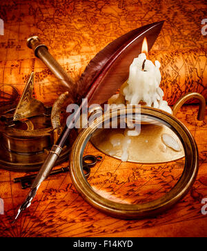 Vintage compas, loupe, plume d'oie, spyglass se situent sur une ancienne carte ancienne en 1565 avec une bougie allumée. Vintage still life. Banque D'Images