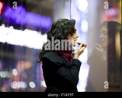 USA, New York City, Manhattan, Times Square, jeune femme à l'aide de rouge à lèvres Banque D'Images