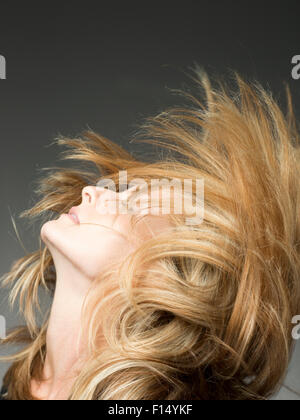 Blonde woman flipping hair in studio Banque D'Images