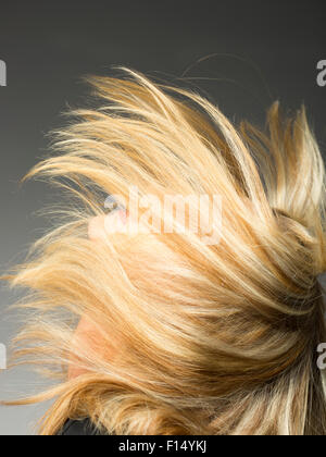Blonde woman flipping hair in studio Banque D'Images