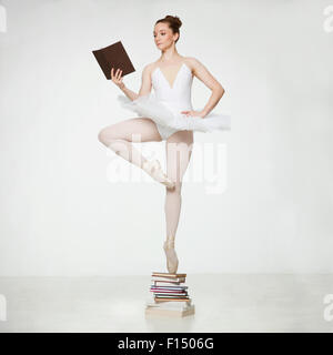 Studio shot of ballet dancer balancing on pile of books Banque D'Images