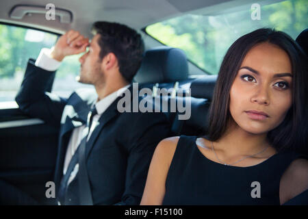 Businessman and businesswoman riding sur siège arrière dans... Banque D'Images