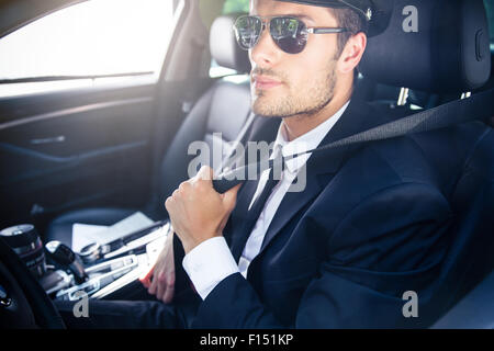 Portrait d'un beau mâle chauffeur en lunettes assise dans une voiture Banque D'Images