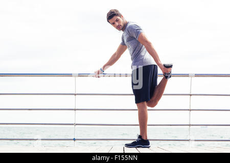 Portrait d'un homme dans les vêtements de sport s'étend à l'extérieur des jambes Banque D'Images