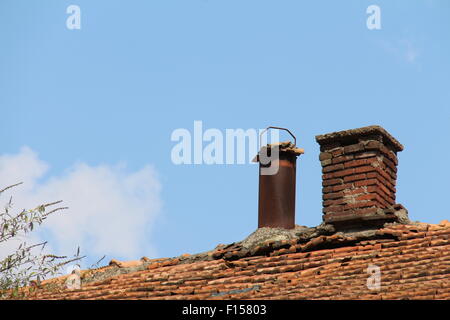 Un détail de la toiture en tuiles de céramique cheminée en brique sur la vieille maison en bois. Banque D'Images