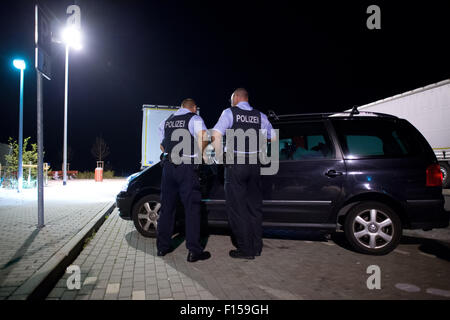 Les agents de police Torsten Bastian et Patrick Thomas (l) vérifier les passagers dans un véhicule pendant leur quart de nuit sur l'aire de repos 'Am Heidenholz' près de la station de police fédérale Breitenau à Bad Gottleuba-BerggieSShuebel, Allemagne, 24 août 2015. Photo : ARNO BURGI/dpa Banque D'Images