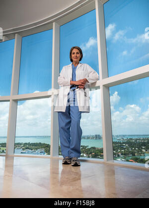 Mature female doctor holding stethoscope fenêtre, debout près de Banque D'Images