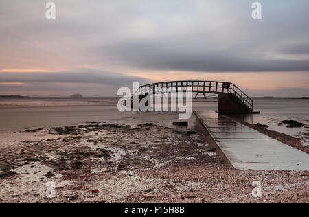 Escaliers vers nulle part au coucher du soleil avec la grosse roche dans la distance Banque D'Images