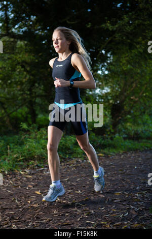 Jogging féminin dans l'emplacement des bois Banque D'Images