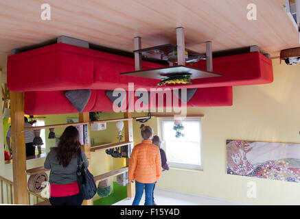 Wolgast, Allemagne. Août 25, 2015. Les visiteurs se tenir en face d'une table à l'intérieur d'une maison qui est à l'envers à Wolgast, Allemagne, 25 août 2015. Deux hommes d'affaires de Stettin en Pologne a construit la maison dans laquelle toutes les choses sont à l'envers sur l'île Usedom en 2008. Le projet 'Die Welt steht Kopf" (lit. 'Le monde est à l'envers') est devenu un aimant pour les visiteurs et attire jusqu'à 50 000 visiteurs par an. Photo : STEFAN SAUER/dpa/Alamy Live News Banque D'Images