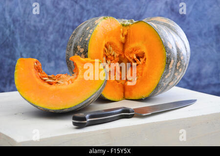 La préparation des aliments pour l'automne ou repas de Thanksgiving avec citrouille coupe tranche sur grande planche de bois blanc en bleu et blanc cuisine e Banque D'Images