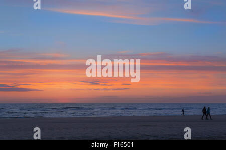 Les personnes bénéficiant d'un coucher du soleil à pied sur la plage de Katwijk aan Zee, Hollande méridionale, Pays-Bas. Banque D'Images