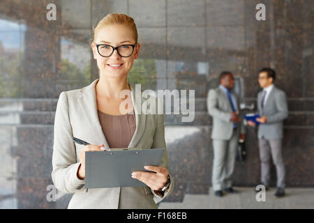 Les jeunes au sérieux à la businesswoman smiling at camera Banque D'Images