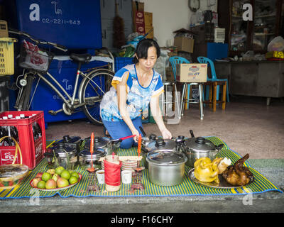 Bangkok, Bangkok, Thaïlande. Août 28, 2015. Une femme laisse un banquet de la nourriture pour ses ancêtres à esprit affamé dans le quartier chinois de Bangkok de jour. Les Bouddhistes Mahayana croient que les portes de l'enfer sont ouvertes sur la pleine lune du septième mois lunaire du calendrier chinois, et les esprits des fantômes affamés admis pour parcourir la terre. Ces fantômes ont besoin de nourriture et de mérite à trouver leur chemin de retour à leur propre. Les gens à s'aider en offrant de la nourriture, l'argent en papier, des bougies et des fleurs, ce qui en mérite de leur propre dans le processus. Esprit affamé jour est observé dans les communautés avec une grande population d'origine chinoise comme Banque D'Images