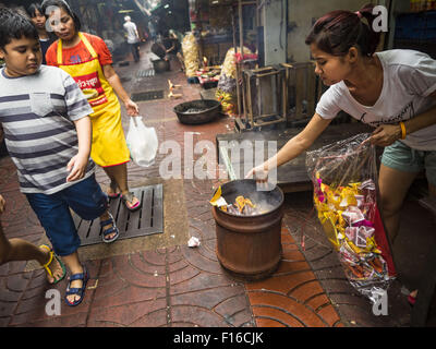 Bangkok, Bangkok, Thaïlande. Août 28, 2015. Une femme burns ''ghost'' de l'argent pour ses ancêtres sur l'esprit affamé dans le quartier chinois de Bangkok de jour. Les Bouddhistes Mahayana croient que les portes de l'enfer sont ouvertes sur la pleine lune du septième mois lunaire du calendrier chinois, et les esprits des fantômes affamés admis pour parcourir la terre. Ces fantômes ont besoin de nourriture et de mérite à trouver leur chemin de retour à leur propre. Les gens à s'aider en offrant de la nourriture, l'argent en papier, des bougies et des fleurs, ce qui en mérite de leur propre dans le processus. Esprit affamé jour est observé dans les communautés avec une grande population d'origine chinoise comme Bangkok Banque D'Images