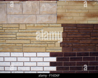 Mur de fragment avec différents types de revêtement décoratif imitant la pierre naturelle ou de briques de blanc, marron et beige pour Banque D'Images