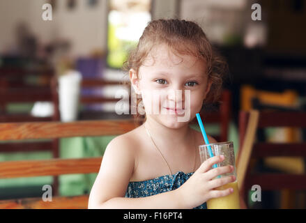 Happy smiling kid girl drinking jus frais à partir de café en verre Banque D'Images