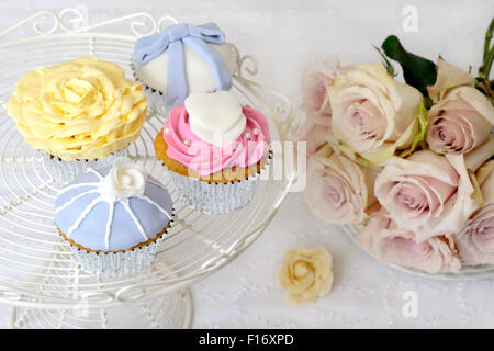 Petits gâteaux de mariage en bleu glacé dessins rose et jaune. Banque D'Images