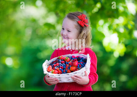 La cueillette à la ferme. Little girl eating fraise, framboise, myrtille, mûre, de groseille rouge et noir. Banque D'Images