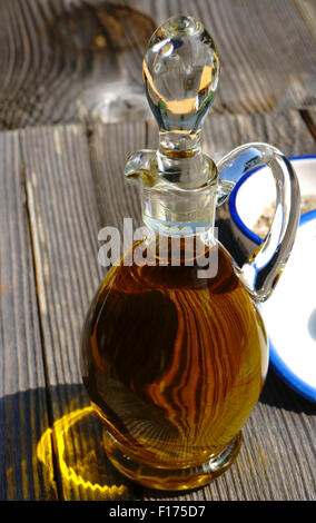 Carafe en verre avec de l'huile d'olive d'or sur une table en bois rustique Banque D'Images