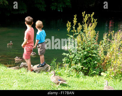 Deux jeunes garçons à regarder les canards au bord de la rivière, Marlborough, Wiltshire, Royaume-Uni Banque D'Images