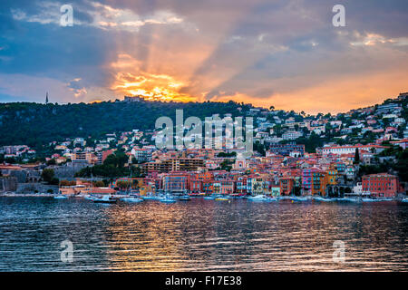 Vue de la Côte d'Azur ville de Villefranche-sur-Mer au coucher du soleil spectaculaire avec du soleil se reflétant dans le port. Banque D'Images