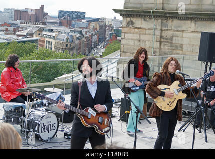 Liverpool, Royaume-Uni. Août 29, 2015. Beatles les Beatles, un groupe hommage écossais, recréé la dernière performance publique des Beatles sur le toit de l'administration centrale d'Apple en 1969 en jouant sur le dessus de la bibliothèque centrale de Liverpool le samedi après-midi, le 29 août. Il a fait partie de l'International Beatleweek de célébrations. Credit : Pak Hung Chan/Alamy Live News Banque D'Images