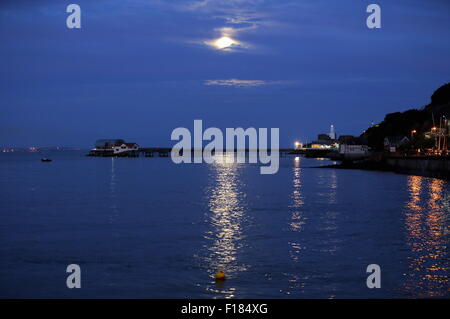 Swansea, Royaume-Uni. Le samedi 29 août 2015 la pleine lune est dans la mer scintillante comme il est en hausse à travers les nuages minces au cours de la RNLI boat house de Mumbles Pier, près de Swansea, Royaume-Uni. Banque D'Images