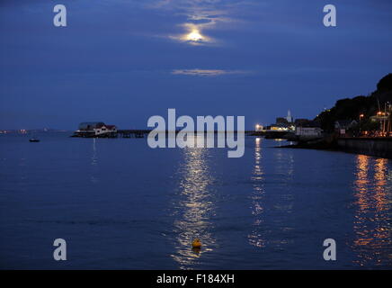 Swansea, Royaume-Uni. Le samedi 29 août 2015 la pleine lune est dans la mer scintillante comme il est en hausse à travers les nuages minces au cours de la RNLI boat house de Mumbles Pier, près de Swansea, Royaume-Uni. Banque D'Images