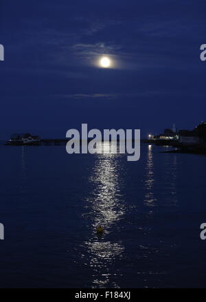 Swansea, Royaume-Uni. Le samedi 29 août 2015 la pleine lune est dans la mer scintillante comme il est en hausse à travers les nuages minces au cours de la RNLI boat house de Mumbles Pier, près de Swansea, Royaume-Uni. Banque D'Images