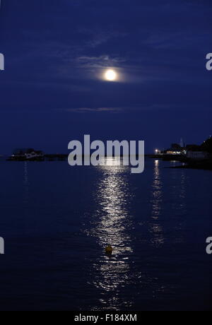 Swansea, Royaume-Uni. Le samedi 29 août 2015 la pleine lune est dans la mer scintillante comme il est en hausse à travers les nuages minces au cours de la RNLI boat house de Mumbles Pier, près de Swansea, Royaume-Uni. Banque D'Images