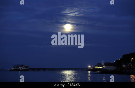 Swansea, Royaume-Uni. Le samedi 29 août 2015 la pleine lune est dans la mer scintillante comme il est en hausse à travers les nuages minces au cours de la RNLI boat house de Mumbles Pier, près de Swansea, Royaume-Uni. Banque D'Images