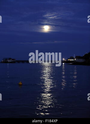 Swansea, Royaume-Uni. Le samedi 29 août 2015 la pleine lune est dans la mer scintillante comme il est en hausse à travers les nuages minces au cours de la RNLI boat house de Mumbles Pier, près de Swansea, Royaume-Uni. Banque D'Images